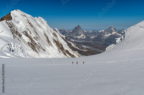 Group of mountaneers walking on a glacier in a sunny day photo