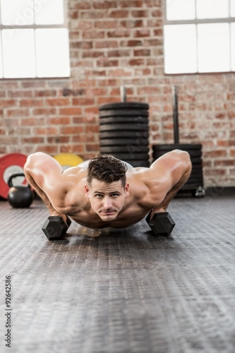 Portrait of shirtless man doing dumbbell push ups