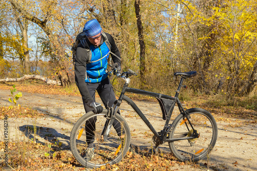 Active man with bicycle in a autumn forest.