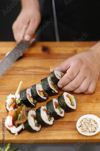 Sushi.Sushi master kroi nożem rolki sushi