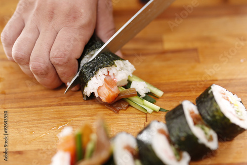 Krojenie sushi. Sushi master kroi nożem rolki sushi
