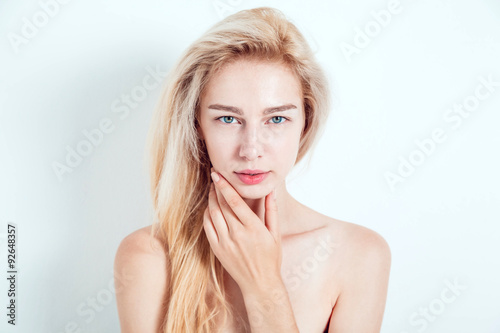 Beautiful blond with green eyes on a light background. She looks into the camera. Fashionable hair color. A good manicure.