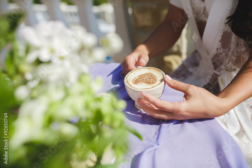 Bride in negligee holding cappuccino at a wedding day