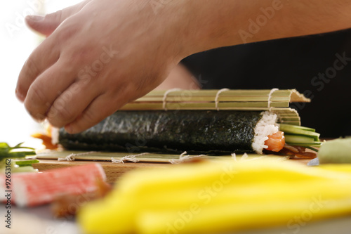 Sushi , etapy przygotowywania sushi z łososiem, paluszkiem krabowym, ogórkiem tykwą zawiniętego w glon nori