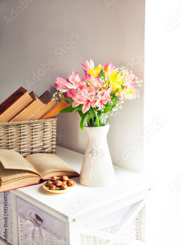 Alstroemeria flowers with cherries and book in vase
