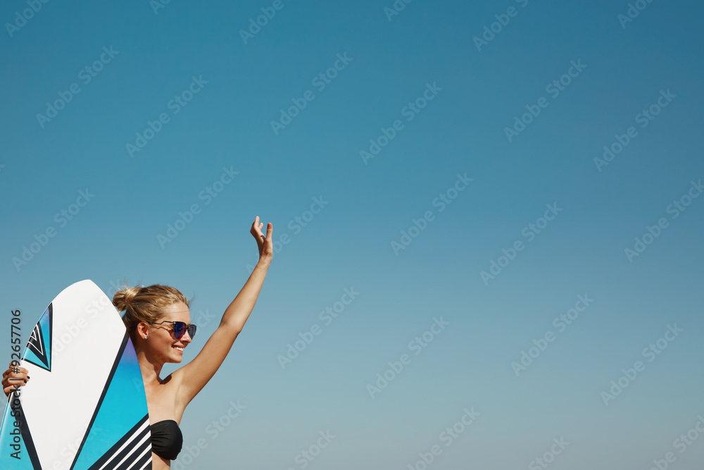 Blonde girl dressed in swimsuit standing on the ocean ready to surfing, female surfer holding surfboard. sky copy-space Blonde girl dressed in swimsuit standing on the ocean ready to surfing, female surfer holding surfboard. sky copy-space