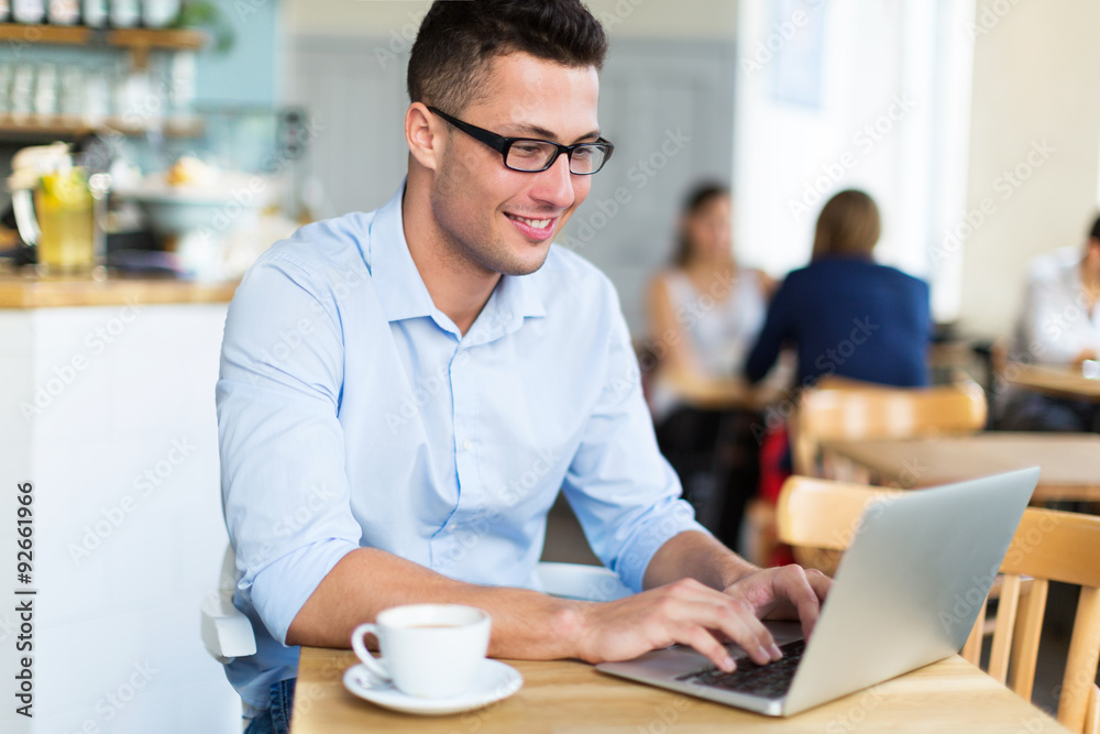 Young man using laptop at cafe