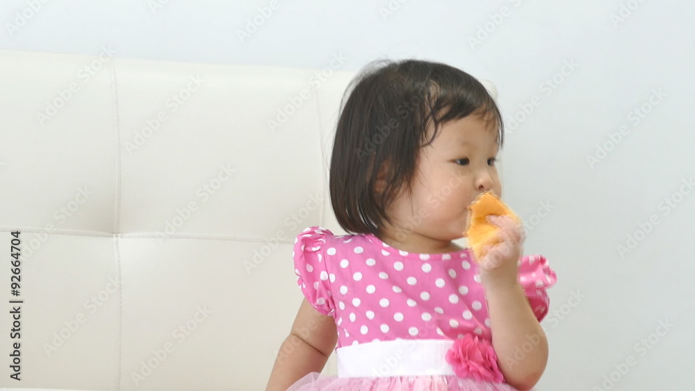 Little Asian child standing and eating cake Little Asian child standing and eating cake