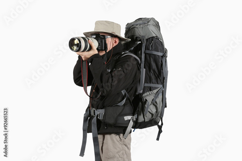 tourist in a black jacket and a hat with a backpack taking photo