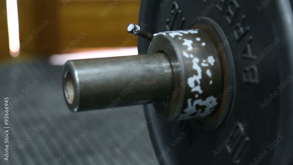 The athlete secures the lock on the rod in the gym
The athlete secures the lock on the rod in the gym