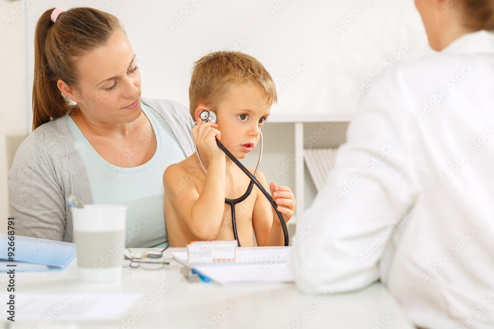 Small boy playing with his doctors stethoscope at the doctors office Small boy playing with his doctors stethoscope at the doctors office