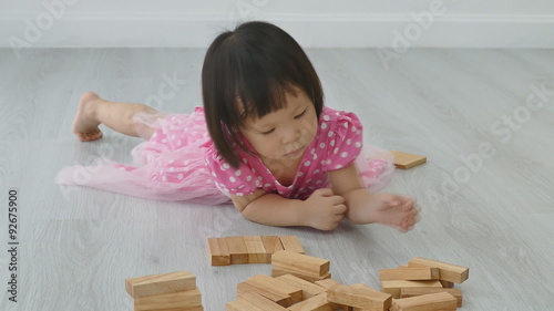 Little asian girl playing with wood blocks on the floor 