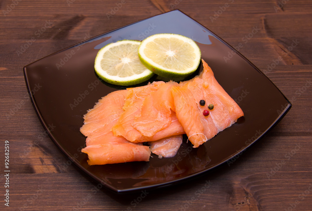 Smoked salmon on black plate on wooden table