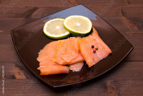 Smoked salmon on black plate on wooden table