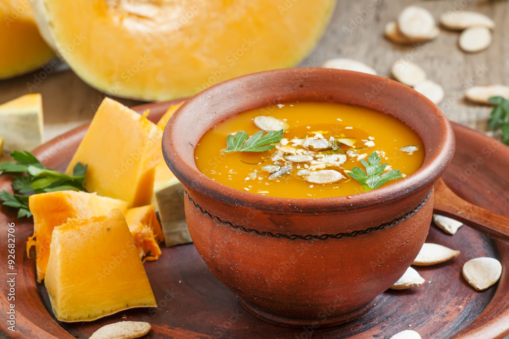Pumpkin soup with oil and seeds in a clay bowl in a rustic style
