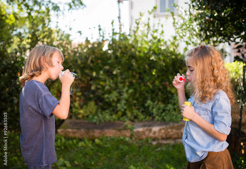Obraz premium Boy and girl blowing soap bubbles
