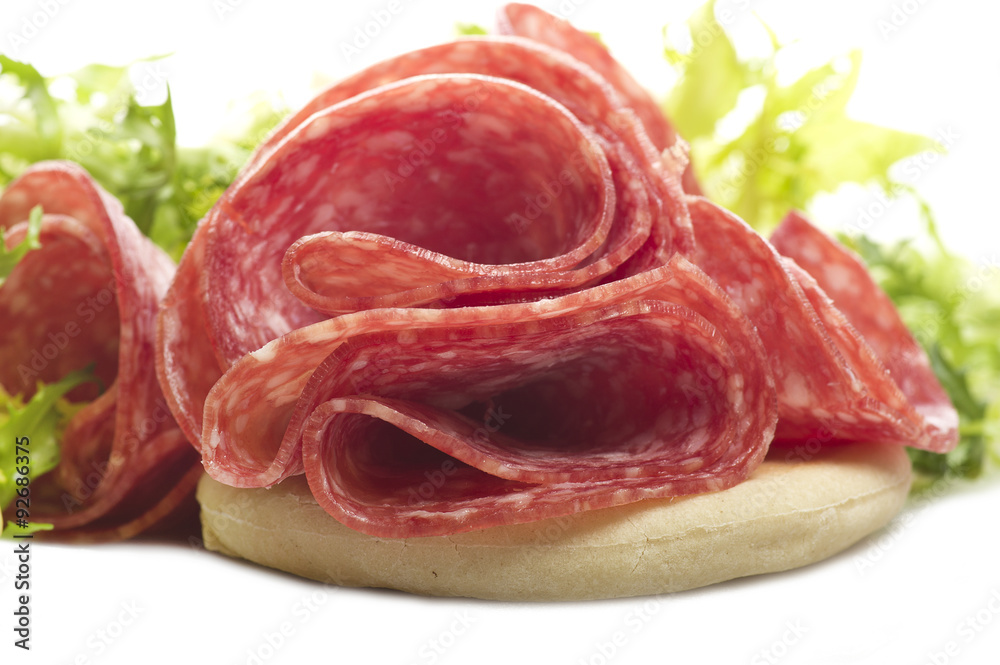 Salami sliced and bread with lattuce on white Salami sliced and bread with lattuce on white