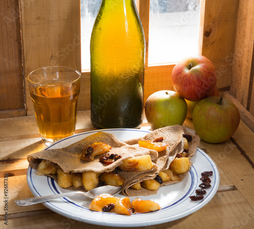 Apple pancakes with a bottle and a glass of cider next to a wind photo