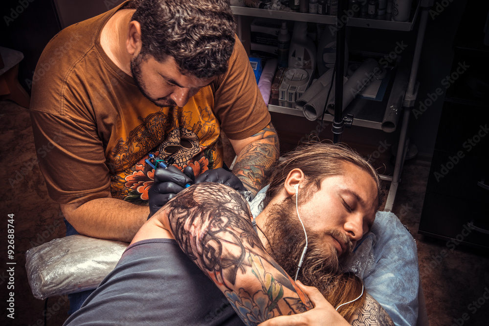 Man wearing gloves makes cool tattoo in tattoo parlour Man wearing gloves makes cool tattoo in tattoo parlour