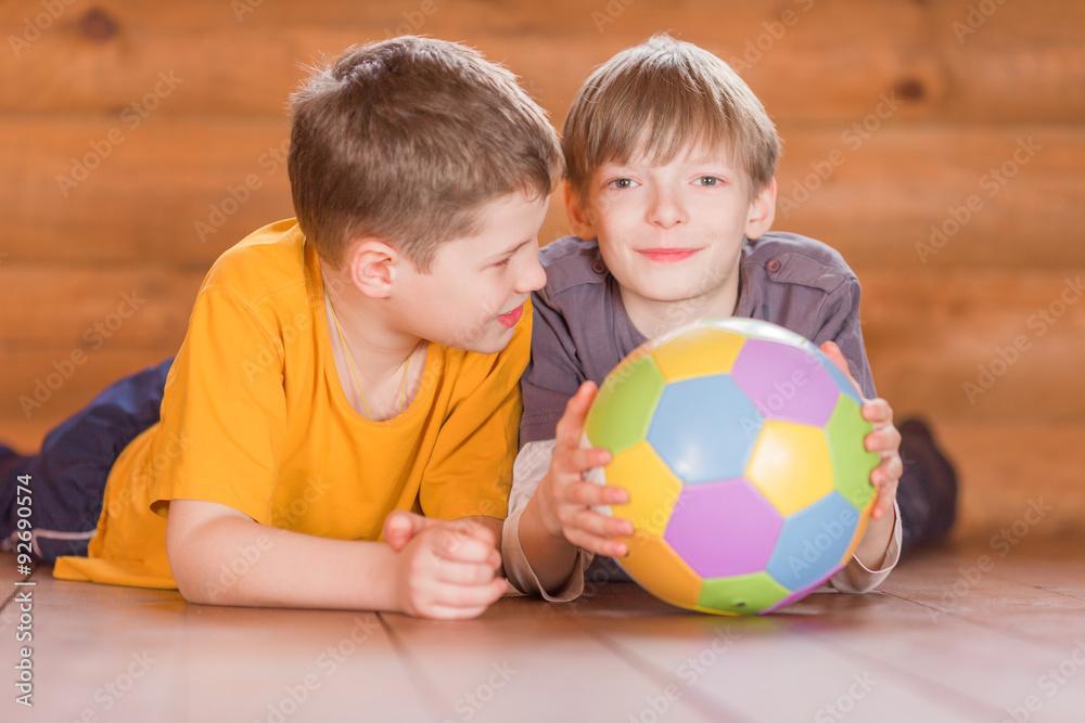 Fototapeta premium Two friends with a ball lying on the floor