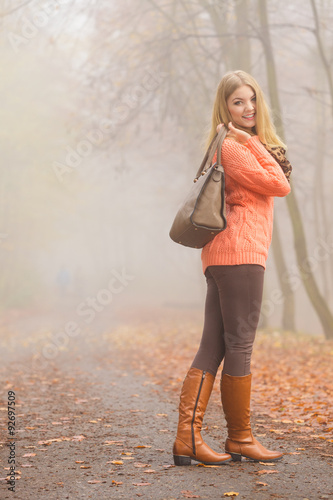 Happy fashion woman with handbag in autumn park