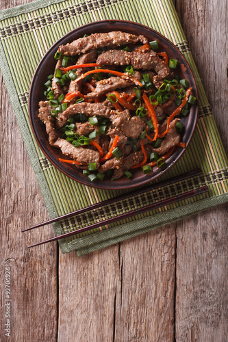 Asian Bulgogi beef slices fried with sesame on a plate. vertical top view
