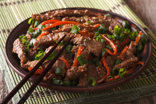 Asian cuisine: slices of beef fried with sesame and carrot close-up
