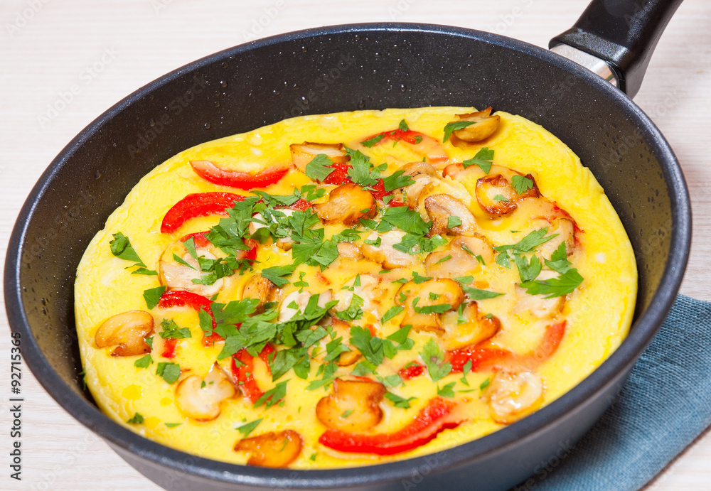 omelet with mushrooms, and vegetables in a frying pan