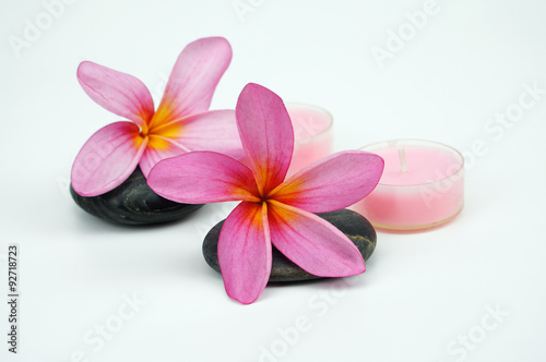 Pink Frangipani flowers on pebble with pink candle isoalted on w