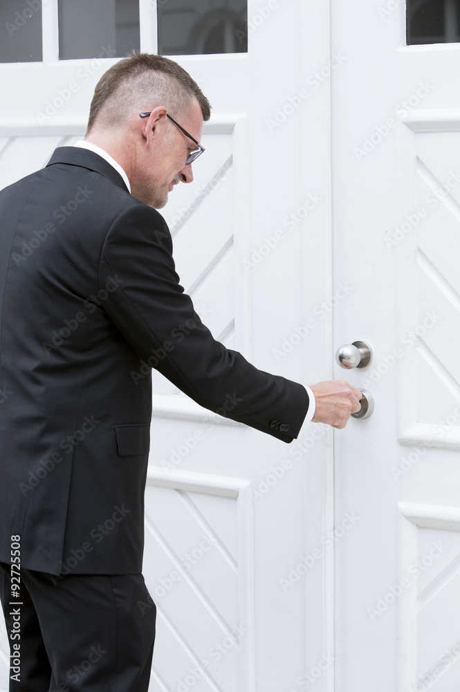 man in suit standing at door with key man in suit standing at door with key