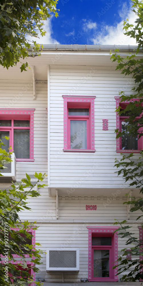 Casa blanca con ventanas rosas entre árboles Stock Photo