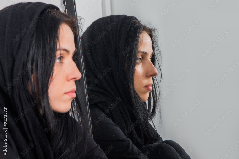 Portrait of serious young woman with covered hair, reflection in mirror
Portrait of serious young woman with covered hair, reflection in mirror