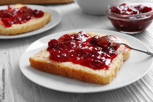 Bread with butter and homemade jam in white plate, closeup