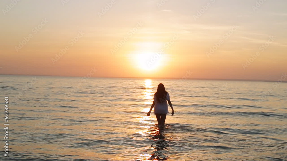 a girl walks into the sea at sunset slow motion a girl walks into the sea at sunset slow motion