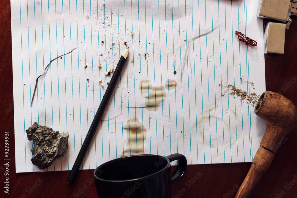 Spilled coffee on paper with pipe, lighter, pencil, paper and coffee cup