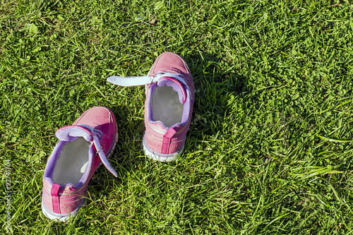 Pink sneakers outside in the grass. Focus on dandelion.