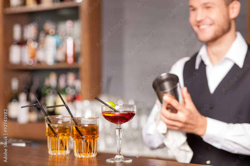 Attractive male bartender is shaking drink in pub