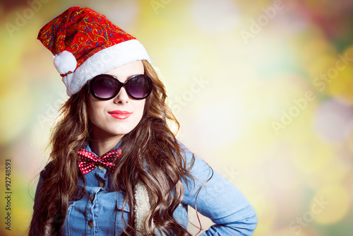 Confident girl in sunglasses wearing xmas santa hat photo