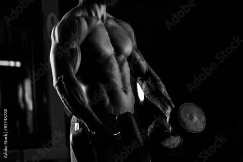 Strong man - bodybuilder with dumbbells in a gym, exercising wit © romanolebedev