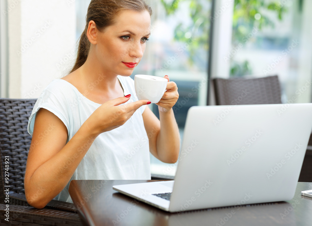 Attractive business woman sitting in a cafe with a laptop and dr Attractive business woman sitting in a cafe with a laptop and dr
