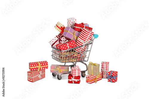 Shopping Cart overfilled with christmas gifts and some fell outside. On white background. © tomalv