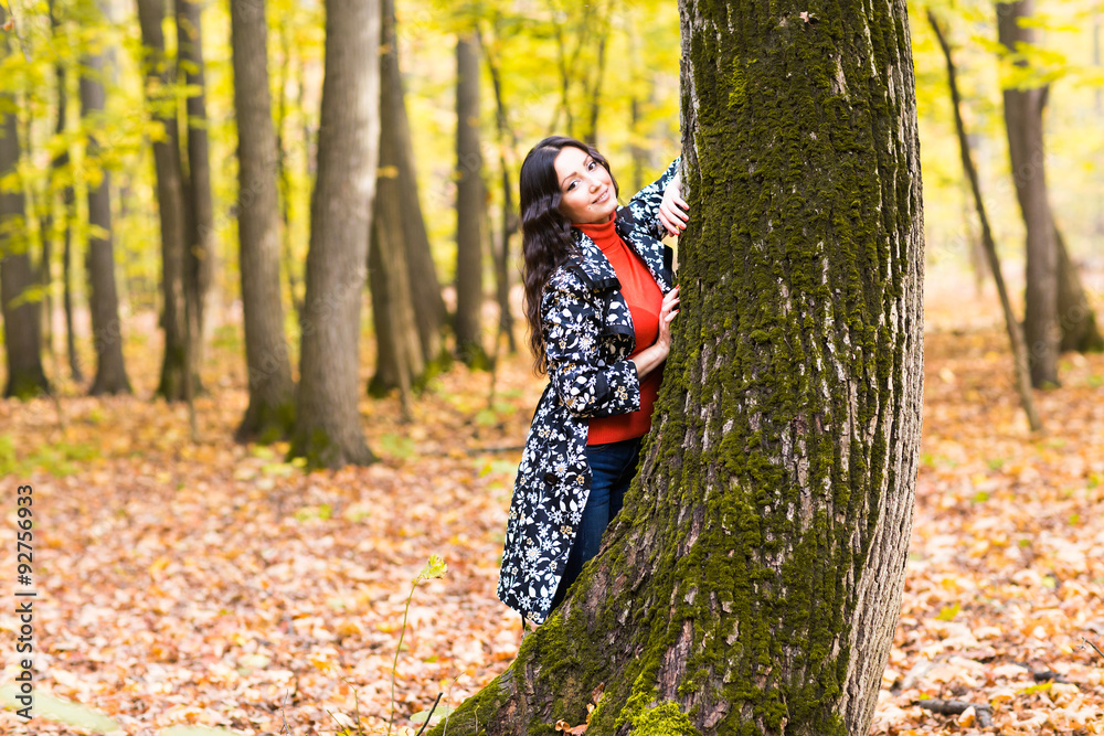 Young pretty girl standing near a tree  in autumn park
