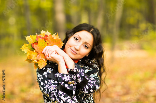  girl holding autumn leaves in fall park