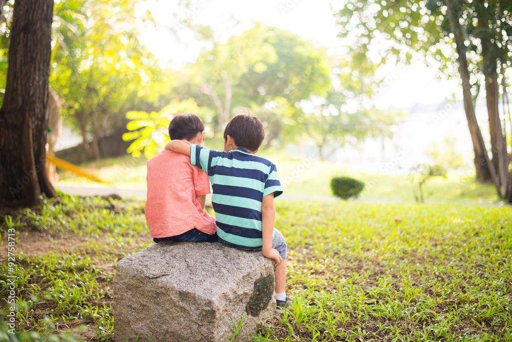 Little sibling boy sitting together in the park Little sibling boy sitting together in the park