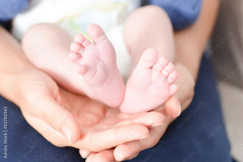 Mother holding baby feet in her palms suggesting parenting affection or love Mother holding baby feet in her palms suggesting parenting affection or love