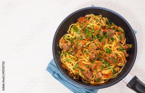 Pieces of meat and vegetables with spaghetti in a frying pan