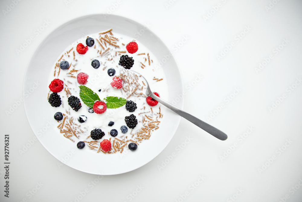 Muesli with milk and berries for breakfast in white dish with sil Muesli with milk and berries for breakfast in white dish with sil