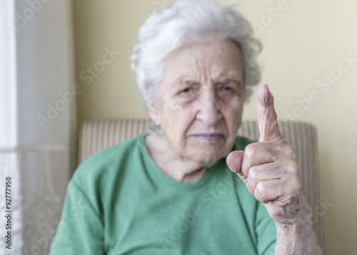 
an angry old woman with her finger up for admonition /warning