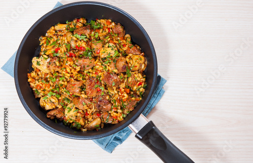 Rice with meat, vegetables and mushrooms in a frying pan