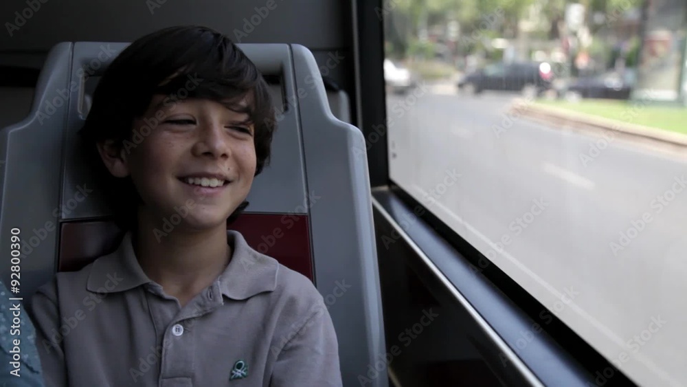 Niño mirando por la ventana del autobús mientras sonríe